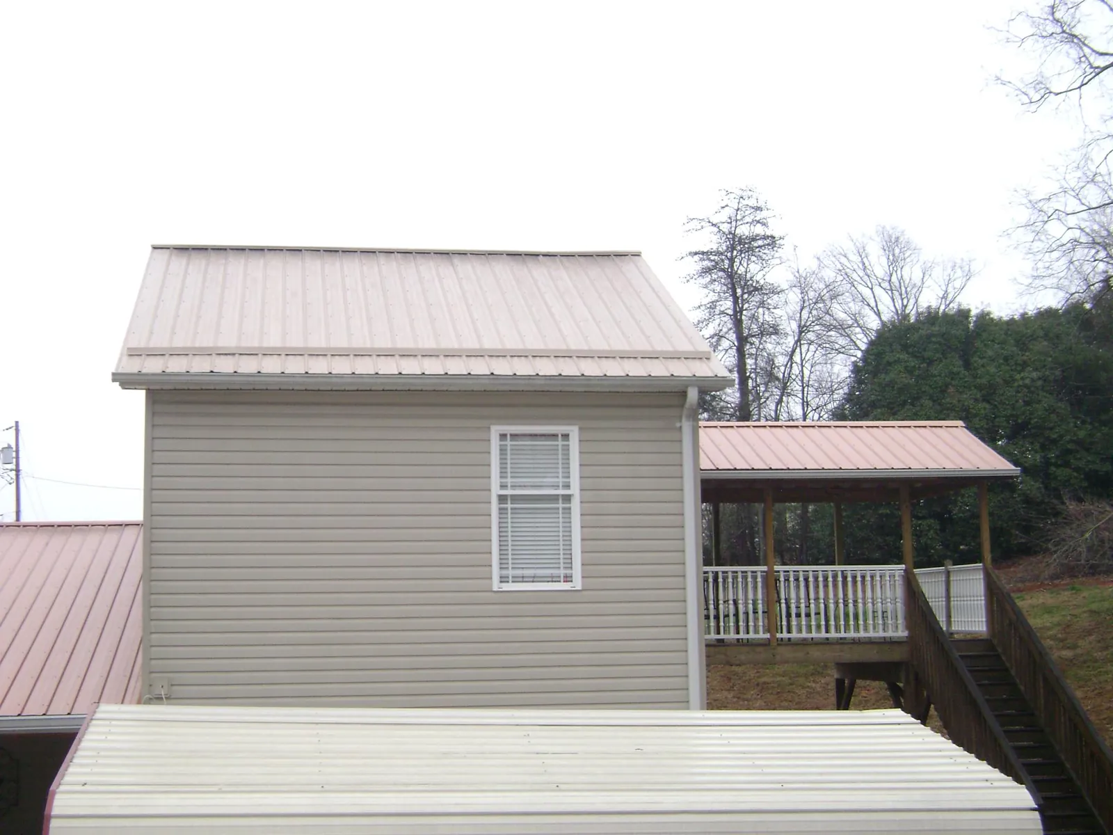 Tan metal roofs on a two story addition and attached porch, from a Roof Replacement job in Buena Vista