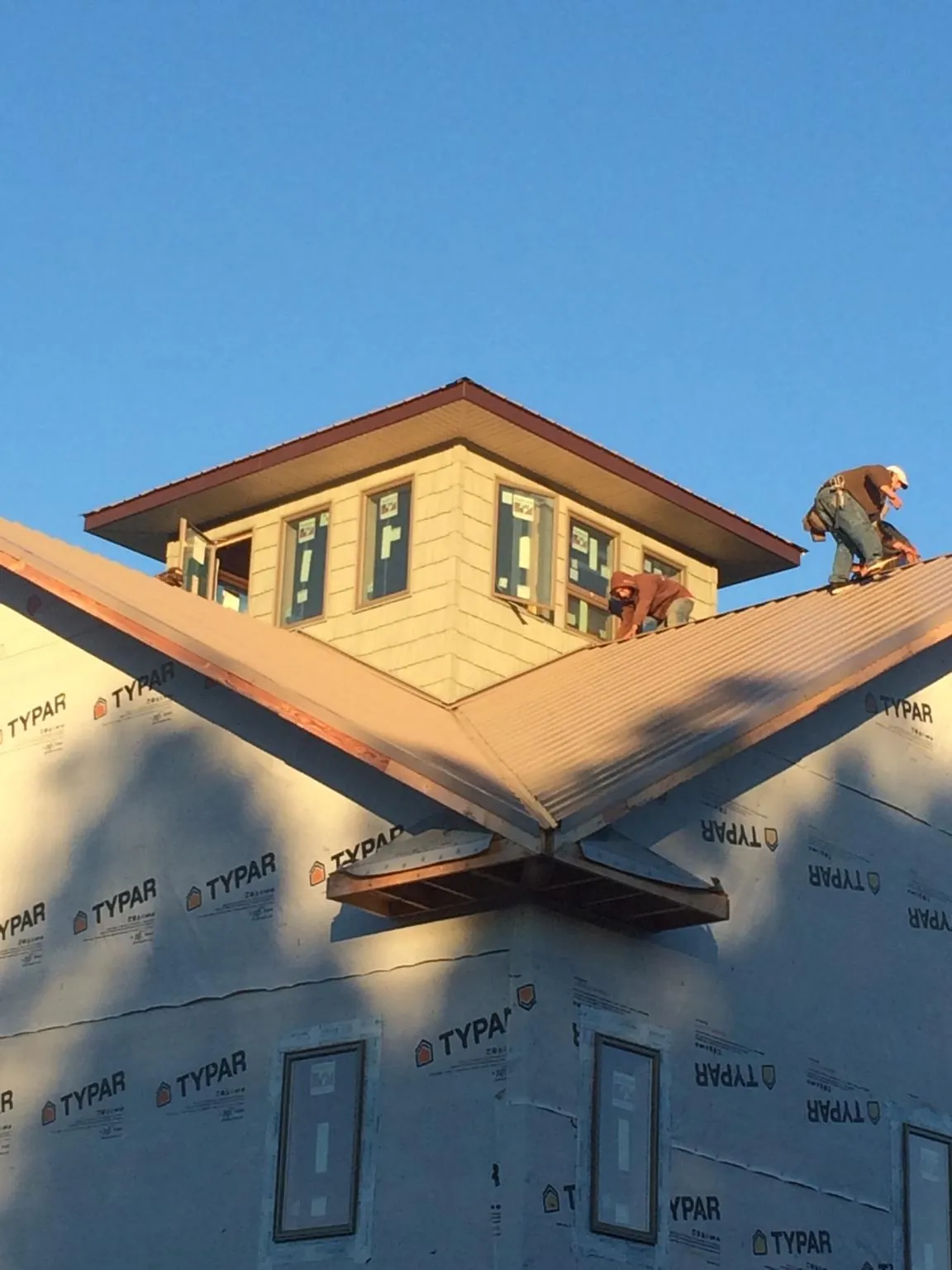 Roofers working around a rooftop cupola on a new metal roof at sunset — Roof Waterproofing in Buena Vista by Roofing Brothers